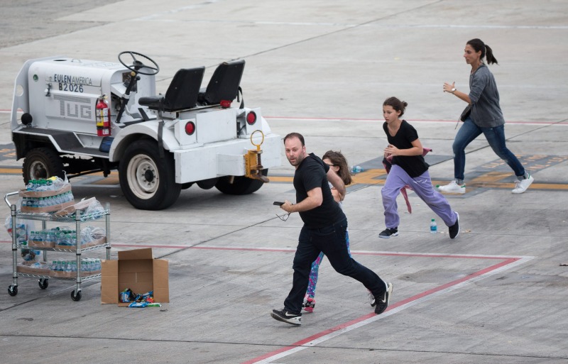 People run on the tarmac at Fort Lauderdale–Hollywood International Airport, Friday, Jan. 6, 2017, in Fort Lauderdale, Fla., after a shooter opened fire inside a terminal of the airport, killing several people and wounding others before being taken into custody. (AP Photo/Wilfredo Lee)
