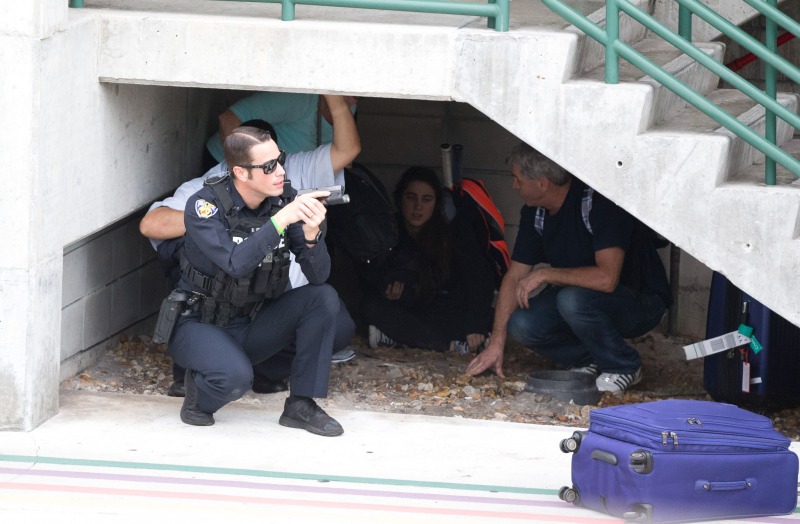 Law enforcement personnel shield civilians outside a garage area at Fort Lauderdale–Hollywood International Airport, Friday, Jan. 6, 2017, in Fort Lauderdale, Fla. A gunman opened fire in the baggage claim area at the airport Friday, killing several people and wounding others before being taken into custody in an attack that sent panicked passengers running out of the terminal and onto the tarmac, authorities said. (AP Photo/Wilfredo Lee)
