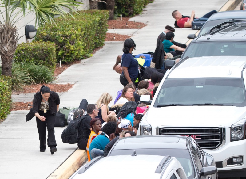 FILE - In this Jan. 6, 2017, file photo, people take cover behind vehicles at Fort Lauderdale–Hollywood International Airport, in Fort Lauderdale, Fla. 2017 in Florida began with tragedy and violence. On Jan. 6 Esteban Santiago flew from Alaska to Fort Lauderdale-Hollywood International Airport, walked into the baggage retrieval area and opened fire, killing five people and wounding six and sending thousands into panic. (AP Photo/Wilfredo Lee, File)