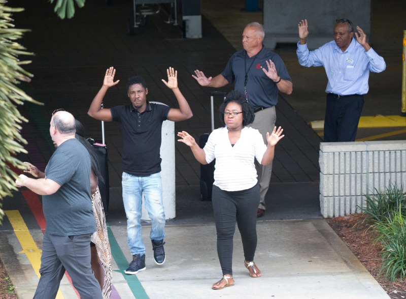 People with their hands up leave a garage area at Fort Lauderdale–Hollywood International Airport, Friday, Jan. 6, 2017, in Fort Lauderdale, Fla. (AP Photo/Wilfredo Lee)
