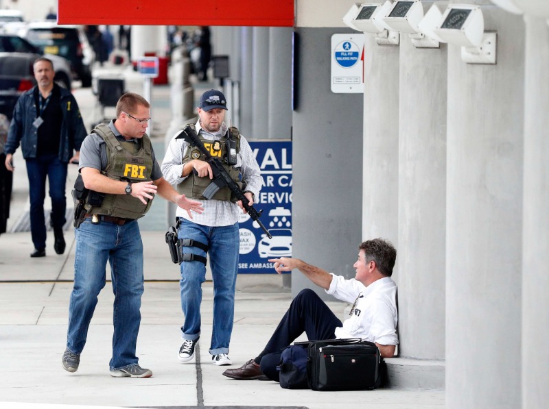 A law enforcement officers talk to a man at Fort Lauderdale–Hollywood International Airport, Friday, Jan. 6, 2017, in Fort Lauderdale, Fla.   A gunman opened fire in the baggage claim area at the airport Friday, killing several people and wounding others before being taken into custody in an attack that sent panicked passengers running out of the terminal and onto the tarmac, authorities said. (AP Photo/Wilfredo Lee)