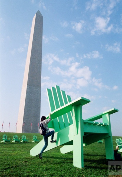 With the Washington Monument in the background, Shih Wei Huang of Taiwan climbs a 14-foot-high Adirondack Chair, Thursday, Oct. 17, 1996, in Washington. The chair is part of a project by the St. Paul, Minn. Green Chair Project which promotes youth skill-building, the arts and education. The chairs' message to the youths is: take time to sit, talk, think and learn. (AP Photo/Wilfredo Lee)