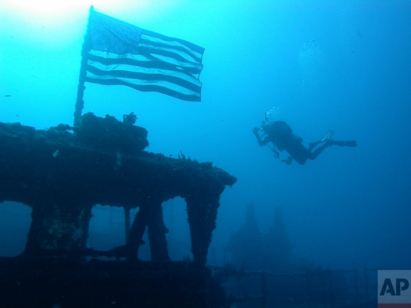 A scuba diver swims near an American flag on the USS Spiegel Grove, Sunday, July 23, 2006 near Key Largo, Fla. The 510 ft. long Landing Ship Dock (LSD 32) was sunk in 2002 at a depth of about 134 ft., to creat an artificial reef. (AP Photo/ Wilfredo Lee)