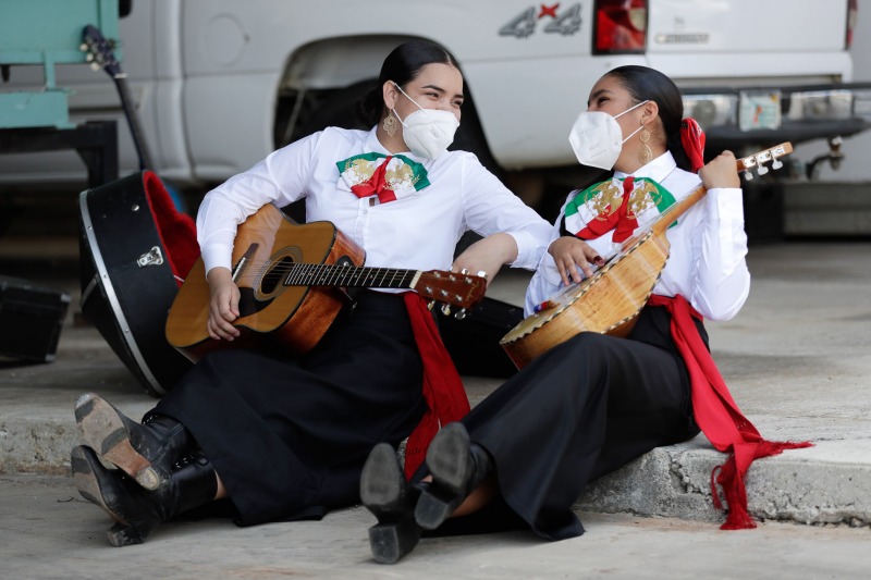 Guitar player Diana Angulo, left, 15, and vihuela player Gimena Arellano, 15, share a laugh as they practice before a performance by the Homestead-Miami Mariachi Conservatory for Altísimo Live!, a livestreamed Latin music and pop culture festival celebrating farmworkers' contributions during the COVID-19 pandemic, Tuesday, May 5, 2020, on a farm in Homestead, Fla. (AP Photo/Wilfredo Lee)