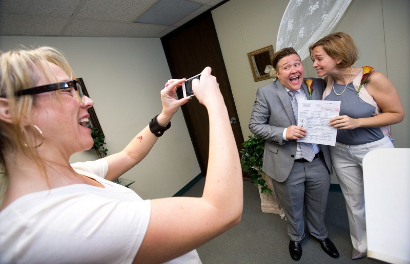 Rebekah Monson, center, 34, and her new spouse Andrea Vigil, right, 37, pose for their friend Miranda Mulligan, left, after they were married at the marriage license bureau, Tuesday, Jan. 6, 2015 in Miami. Miami-Dade Circuit Judge Sarah Zabel presided over Florida's first legally recognized same-sex marriages Monday afternoon. Still, most counties held off on official ceremonies until early Tuesday, when U.S. District Judge Robert L. Hinkle's ruling that Florida's same-sex marriage ban is unconstitutional took effect in all 67 counties. (AP Photo/Wilfredo Lee)
