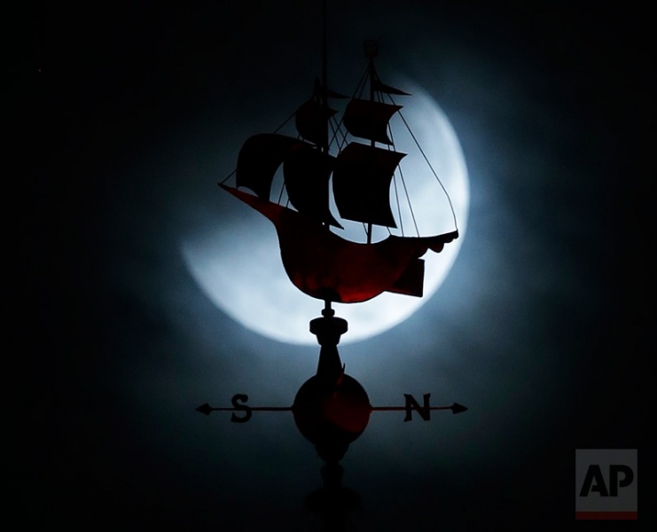 The Earth's shadow begins to fall on the moon during a total lunar eclipse, as it goes behind a weathervane shaped like a Spanish galleon on the Freedom Tower building, Wednesday, Oct. 8, 2014 in Miami. (AP Photo/Wilfredo Lee)