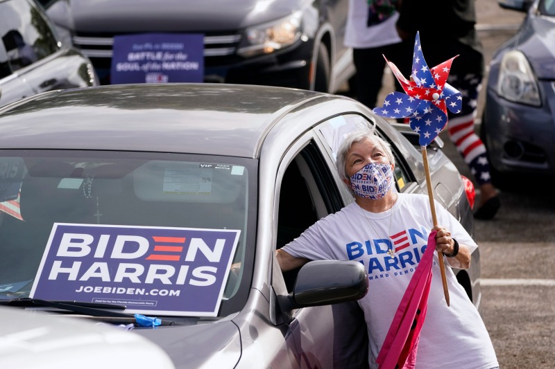 Norma Fisher reaches into her car to honk the horn as she attends a drive-in early voting event for Democratic vice presidential candidate Sen. Kamala Harris, D-Calif., Saturday, Oct. 31, 2020, in Miami, Fla. (AP Photo/Wilfredo Lee)