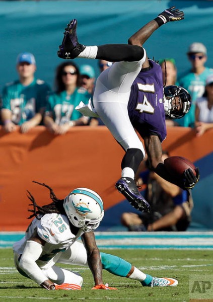 Baltimore Ravens wide receiver Marlon Brown (14) attempts to leap over Miami Dolphins free safety Louis Delmas (25) during the second half of an NFL football game, Sunday, Dec. 7, 2014, in Miami Gardens, Fla. (AP Photo/Wilfredo Lee)