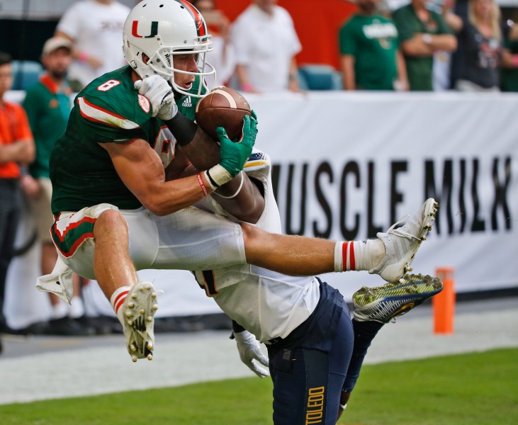 Miami wide receiver Braxton Berrios (8) catches a touch down pass as he is guarded by Toledo safety DeDarallo Blue (21) during the second half of an NCAA College football game, Saturday, Sept. 23, 2017 in Miami Gardens, Fla. Miami defeated Toledo 52-30. (AP Photo/Wilfredo Lee)