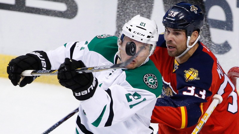 Dallas Stars left wing Antoine Roussel (21) bats the puck as he is guarded by Florida Panthers defenseman Willie Mitchell (33) during the first period of an NHL hockey game, Saturday, Oct. 17, 2015 in Sunrise, Fla. (AP Photo/Wilfredo Lee)