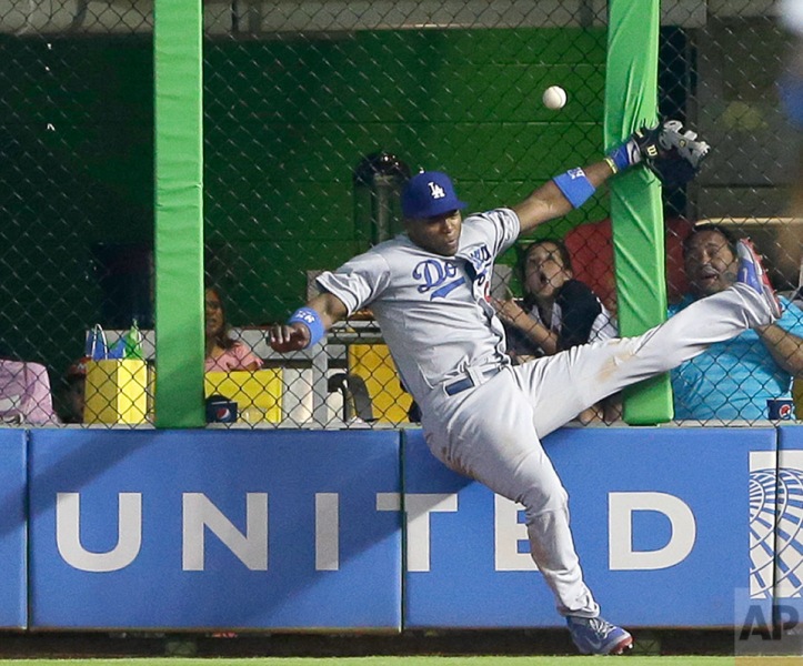 Los Angeles Dodgers right fielder Yasiel Puig is unable to catch a ball at the fence hit by Miami Marlins' Jeff Baker for a double, during the ninth inning of a baseball game, Sunday, May 4, 2014 in Miami. Adeiny Hechavarria scored on the play as the Marlins defeated the Dodgers 5-4. (AP Photo/Wilfredo Lee)