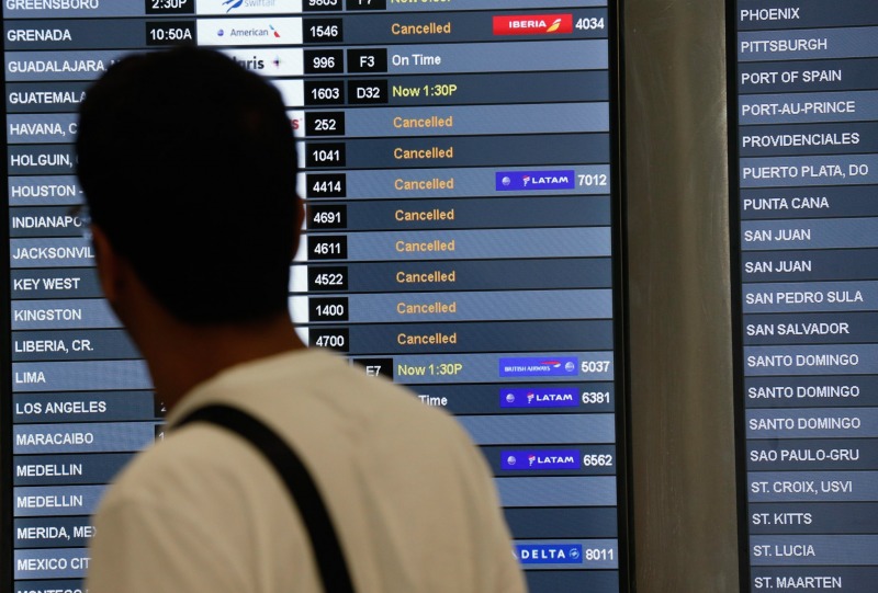 A traveler looks at a monitor listing canceled flights at Miami International Airport, Friday, Sept. 8, 2017 in Miami. Hurricane Irma scraped Cuba's northern coast Friday on a course toward Florida, leaving in its wake a ravaged string of Caribbean resort islands strewn with splintered lumber, corrugated metal and broken concrete. (AP Photo/Wilfredo Lee)