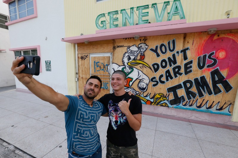 Gustavo Mejia, left, of Miami, and his nephew Juan Sebastian Mejia, of Palmira, Colombia, take a selfie in front of a boarded up hotel on South Beach, Friday, Sept. 8, 2017, in Miami Beach, Fla. Juan Sebastian Mejia was on vacation from Colombia when his flight back home was cancelled. Hurricane Irma aimed its sights on millions of homes and businesses in Florida and officials warned that time was running out to evacuate ahead of the deadly hurricane, which was headed Friday on a long-feared path right through the heart of the peninsula. (AP Photo/Wilfredo Lee)